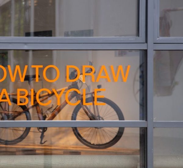 A glass window displays orange and green text reading “HOW TO DRAW A BICYCLE” and exhibition dates, with a bicycle visible inside.